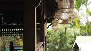 Eine traditionelle Holzstruktur mit einer hängenden dekorativen Lampe und Blick auf üppiges Grün draußen.