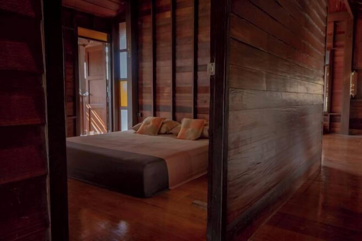 A wooden interior with a bed, a visible door, and a staircase.