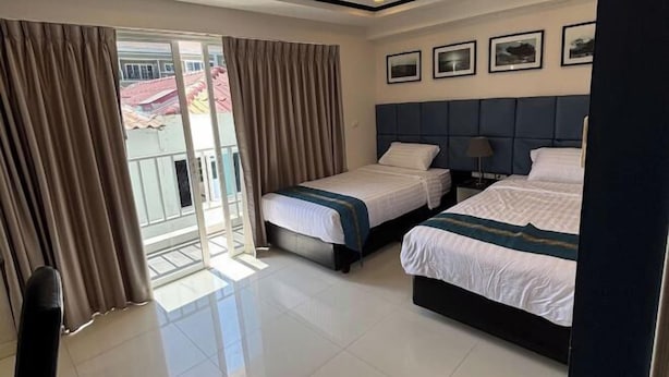 A hotel room with two beds, a large window with curtains, a ceiling light, and framed pictures on the wall. - New Nordic Club 1 Condotel South Pattaya Twin Standard Room (Pattaya)