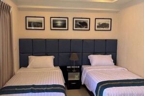 A hotel room with two beds, a headboard, a nightstand, and framed pictures on the wall. - New Nordic Club 1 Condotel South Pattaya Twin Standard Room (Pattaya)