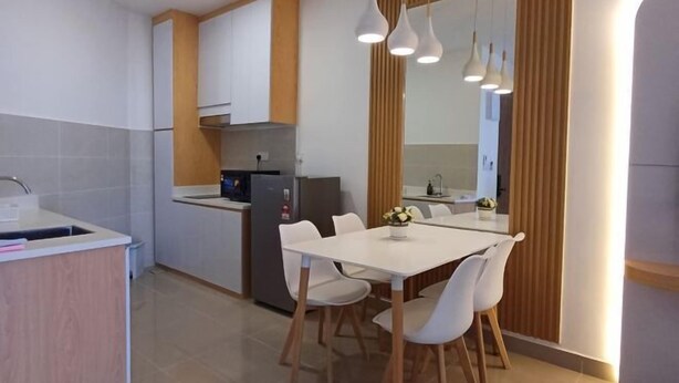 A modern kitchen with white cabinets, a built-in oven, and a dining area with a white table and chairs. - Urban Retreat @ The Shore • CBD • Pool (Kota Kinabalu)
