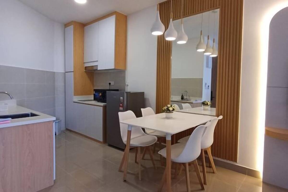 Une cuisine moderne avec des meubles blancs, un four encastré et un coin repas comprenant une table et des chaises blanches.