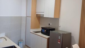 A compact kitchen with white cabinets, a microwave, and a refrigerator. - Urban Retreat @ The Shore • CBD • Pool (Kota Kinabalu)