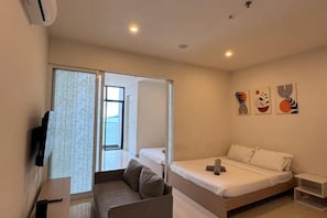 A bedroom with a bed, a sofa, a TV, and artwork on the wall. - Urban Retreat @ The Shore • CBD • Pool (Kota Kinabalu)