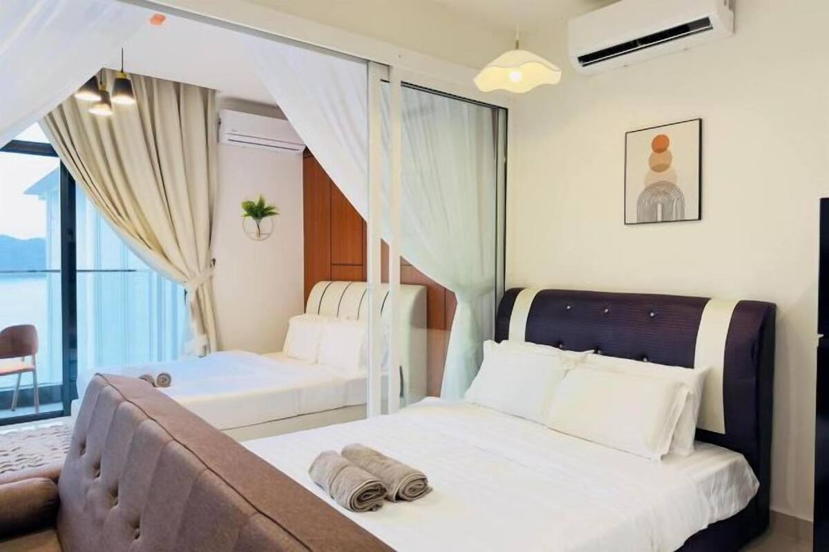 Une chambre d’hôtel comprenant un lit, un canapé, une fenêtre avec des rideaux, un appareil de climatisation et un tableau accroché au mur.