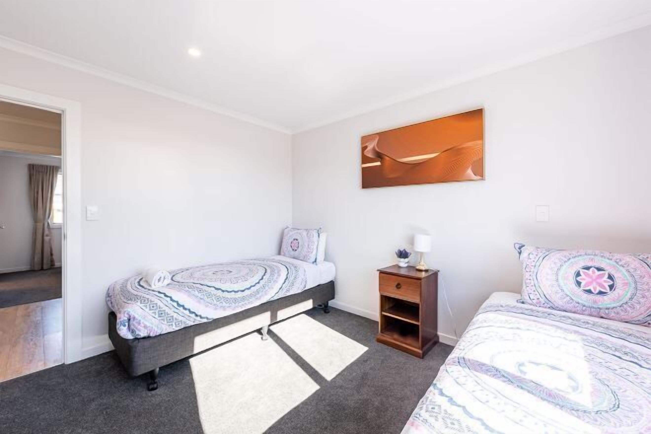 A bedroom with a bed, bedside table, and a wall-mounted artwork.