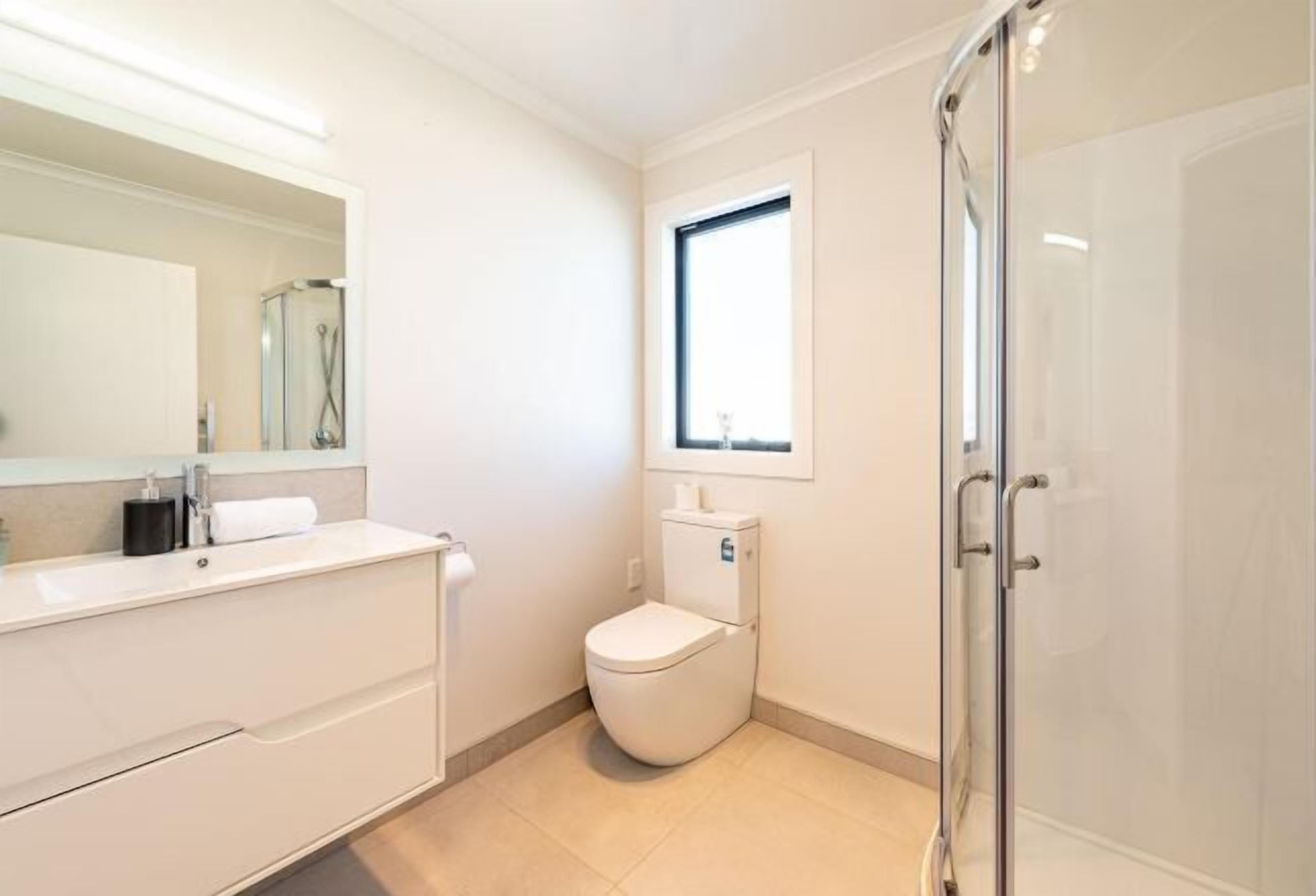 Une salle de bain moderne avec une douche à parois de verre, des toilettes et un meuble-lavabo avec un miroir.
