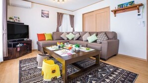 A living room with a sofa, coffee table, TV, and a bookshelf. - Laulea (Kin)