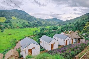 A rural landscape with thatched-roof cottages and terraced fields.