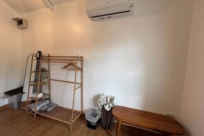 Una habitación con un banco de madera, un perchero y un cubo de basura.
