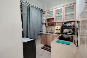 A compact kitchen with a microwave, toaster, and a small sink. - Permai Ria Home Apartment (Tanjung Bungah)