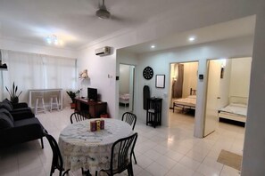A modern living room with a dining table, sofas, and a kitchen area. - Permai Ria Home Apartment (Tanjung Bungah)