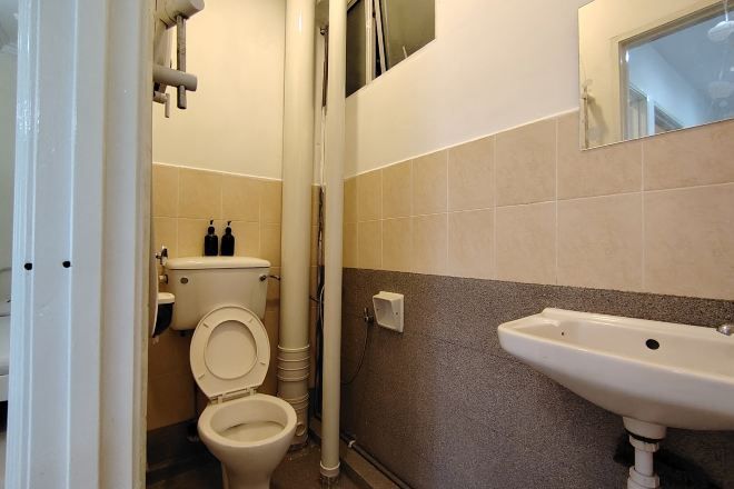 A bathroom with a toilet, sink, and tiled walls.