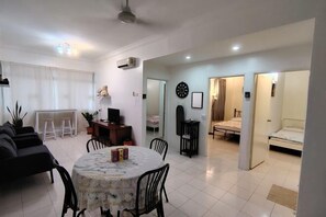 A modern living room with a dining area, a TV, and a cozy seating arrangement. - Permai Ria Home Apartment (Tanjung Bungah)