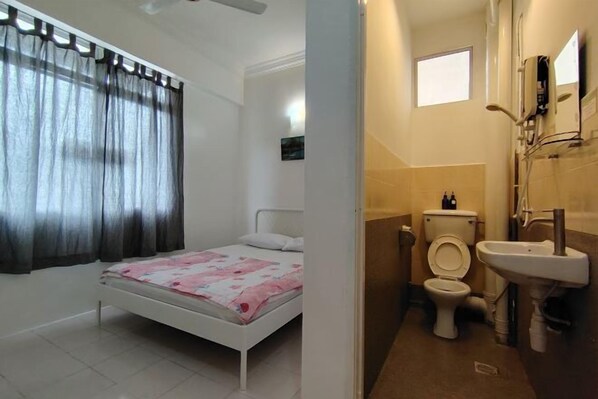 A bedroom with a bed, a window with curtains, a bedside table, and a wall-mounted light fixture. - Permai Ria Home Apartment (Tanjung Bungah)