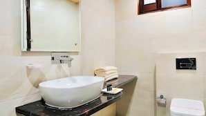 A bathroom with a large white sink, a toilet, and a mirror above the sink. - Hotel Rachna Tourist lodge  (New Delhi)