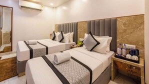 A hotel room with two beds, a marble headboard, a small bedside table with a coffee maker, and a mirror. - Hotel Rachna Tourist lodge  (New Delhi)