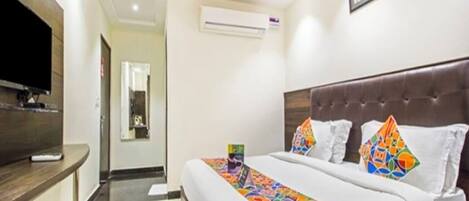 A hotel room with a large bed, a television, and a desk.
