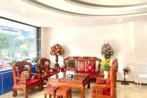 A room with a sofa set, chairs, a coffee table, and a fan. - HN HOTEL (Bac Ninh)