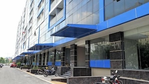 Un bâtiment moderne à la façade bleue, doté de grandes fenêtres et d’un espace d’entrée abrité.