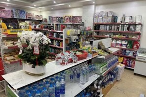 A store with shelves stocked with various products, a display of bottled water, and a floral arrangement on the counter. - HN HOTEL (Bac Ninh)