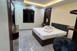 A modern bedroom with a bed, a bedside table, a mirror, and a ceiling fan. - HN HOTEL (Bac Ninh)