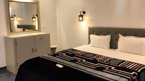 Camera d'albergo moderna con un letto grande, un comodino, una cassettiera, uno specchio e due luci a parete.