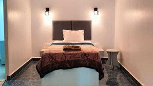 Una camera d'albergo moderna con un letto grande, pavimento in marmo e due luci a parete.