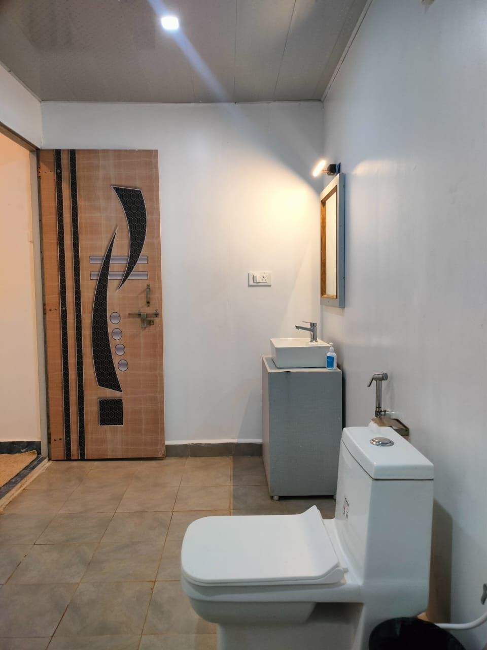 A bathroom with a modern design, featuring a toilet, sink, and mirror.