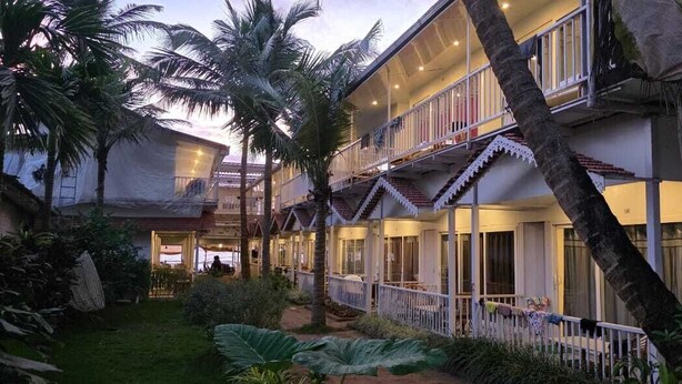Un hotel a più piani con balconi, una zona esterna coperta e una rigogliosa vegetazione tropicale.