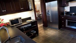 A modern kitchen with dark wood cabinets, stainless steel appliances, and a tiled floor. - Club Med Albion Villas (Mauritius)