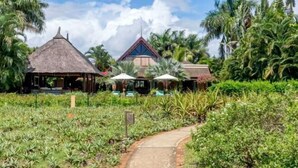A tropical resort with thatched-roof huts, a paved pathway, and lush greenery. - Club Med Albion Villas (Mauritius)