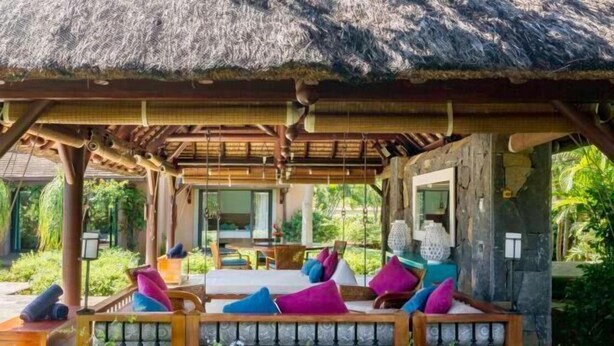 A covered outdoor seating area with cushioned benches and colorful pillows, surrounded by lush greenery. - Club Med Albion Villas (Mauritius)