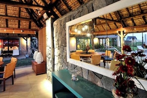 A cozy interior with a stone wall, wooden ceiling, and a large mirror reflecting a dining area. - Club Med Albion Villas (Mauritius)
