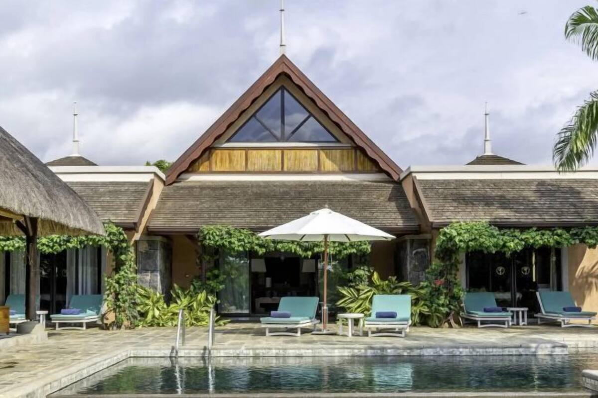 A resort with a pool area, lounge chairs, and a thatched-roof structure.