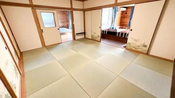 Ett traditionellt japanskt rum med tatamimattor på golvet, skjutdörrar och utsikt över en interiör med träinredning.