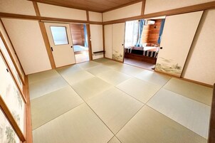 A traditional Japanese room with tatami flooring, sliding doors, and a view of a wooden interior.