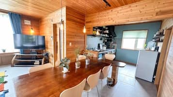 A wooden interior with a dining area, kitchen, and a television.