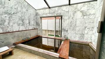 A bathroom with a marble wall, a bathtub, and a window.