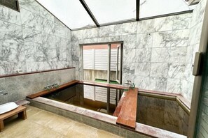 A bathroom with a marble wall, a bathtub, and a window. - Base Shiraoi (Shiraoi)