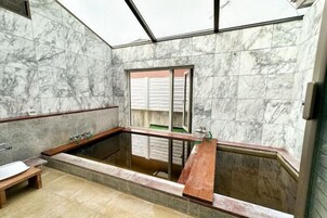 Ein Badezimmer mit Marmorwand, einer Badewanne und einem Fenster.