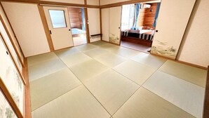 A traditional Japanese room with tatami flooring, sliding doors, and a bed with a wooden headboard. - Base Shiraoi (Shiraoi)