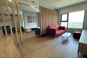A modern interior with a wooden partition, a red sofa, a small round table, and a view through large windows. - Homestay Nha Thu Thu (Hanoi)
