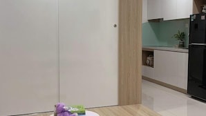 Una cucina moderna con mobili bianchi, un frigorifero nero e una parete decorativa in legno.