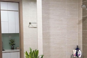 A bathroom with a shower, a towel rack, and a potted plant. - Homestay Nha Thu Thu (Hanoi)