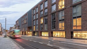 A modern building with large windows and a tram passing by. - Dominick Place (Dublin)
