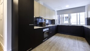 A modern kitchen with black and light wood cabinetry, a built-in oven, and a window providing natural light. - Dominick Place (Dublin)