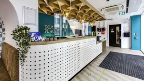 A reception area with a modern design, featuring a reception desk, a sign that reads "DOMINICK PLACE," and a wall-mounted plant. - Dominick Place (Dublin)