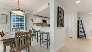 A modern kitchen with white cabinets, a microwave, and a hanging light fixture.
