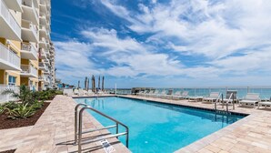 A swimming pool with lounge chairs and a view of the ocean.